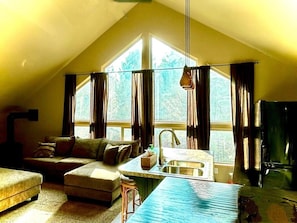 A cozy attic room with a kitchenette, large windows, and a sofa. - Glentree’s Private Loft, Kitchen, Yellowstone, Lakes, Fun (Island Park)