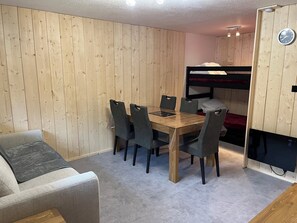 A compact room with a wooden bunk bed, a dining table with chairs, and a sofa. - Chalet-style Mont Dore apartment at the foot of the slopes with mountain views! (Le Mont Dore)