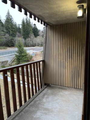 A balcony with a wooden railing, a corrugated metal wall, and a concrete floor. - Chalet-style Mont Dore apartment at the foot of the slopes with mountain views! (Le Mont Dore)