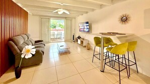 A modern living room with a sofa, a coffee table, and a dining area with chairs. - La Kaz Pêcheur, Calm (La Possession)