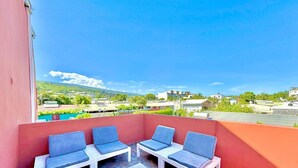 A balcony with four lounge chairs and a table, overlooking a residential area with houses and greenery. - La Kaz Pêcheur, Calm (La Possession)