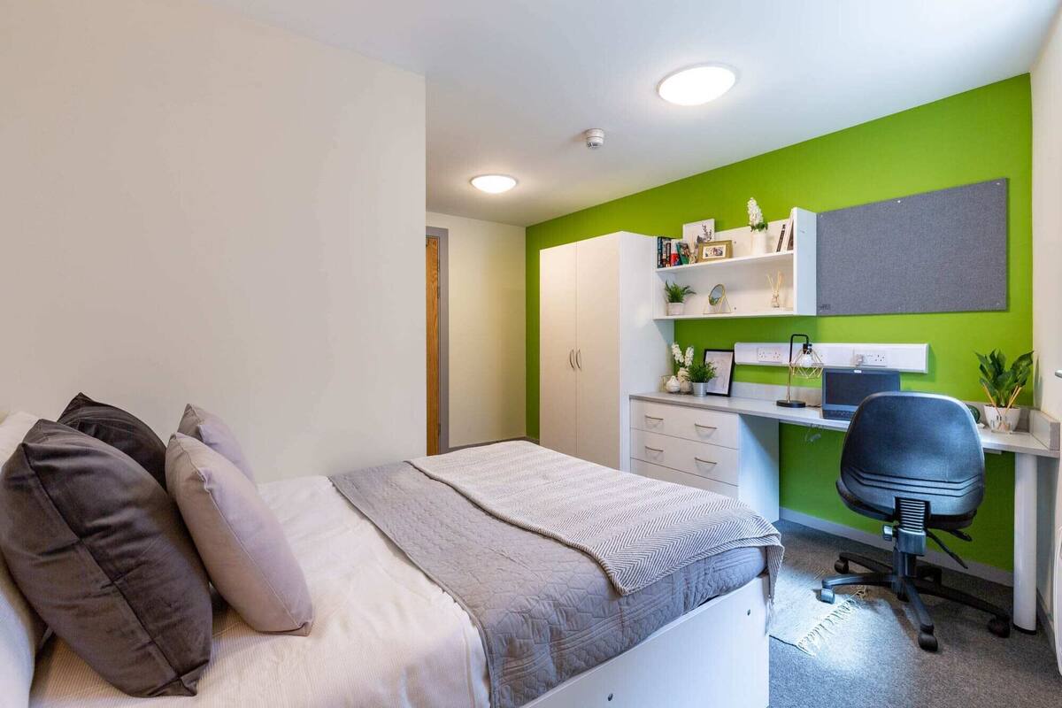 A bedroom with a bed, a desk, and a chair.