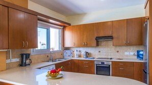 Een moderne keuken met houten kastjes, een groot eiland, een koffiezetapparaat, een waterkoker en een vaatwasser.