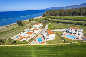 A coastal residential area with multiple houses, a swimming pool, and a view of the sea. - Villa Chrystalla by Villa Plus (Poli Crysochous)