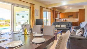Een eethoek met een tafel voor vier personen, een bank en een keuken op de achtergrond.