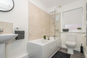 Un baño moderno con un lavamanos, bañera y retrete blancos.