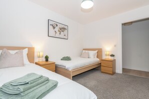 Una habitación de hotel con dos camas individuales, un mapa mundial en la pared y lámparas de noche.