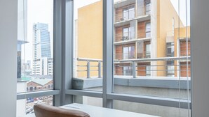 Un espacio de oficina moderno con un amplio ventanal que da a un paisaje urbano y un edificio con balcones.