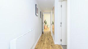 Ein Korridor mit weißen Wänden, Holzboden und gerahmten Bildern.