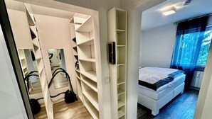 Een slaapkamer met een bed, een inloopkast en uitzicht op bomen door het raam.