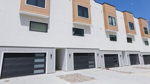 Ein modernes, mehrgeschossiges Wohngebäude mit einer Reihe von Garagen und einem klaren, minimalistischen Architekturstil.
