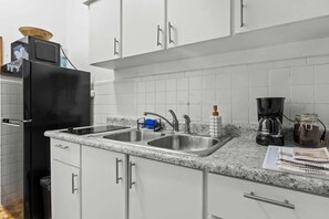 A modern kitchen with white cabinets, a black refrigerator, a double sink, and a coffee maker. - Apartment 2Bedroom Next To La Placita Santu 2B (San Juan)