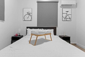 A minimalist bedroom with a large bed, a wooden bedside table, and two nightstands. - Right Next To "La Placita" Apartment! Santu1A (San Juan)