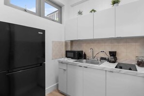 A modern kitchen with a black refrigerator, a microwave, a sink, and a coffee maker.