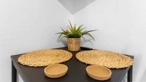 Une petite table d’angle agrémentée d’un set de table en fibres tressées, d’une petite plante en pot et de deux bols en bois.