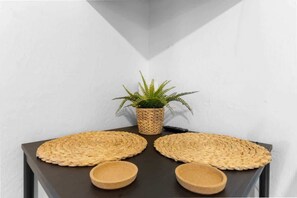 A corner table with a woven placemat, a small potted plant, and two wooden bowls.