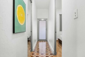 Ein Korridor mit einem gemusterten Boden, einer Tür am Ende und einem gerahmten Kunstwerk an der Wand.