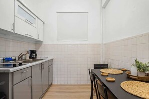Une cuisine moderne avec des meubles gris, un plan de travail noir et une fenêtre au-dessus de l’évier.