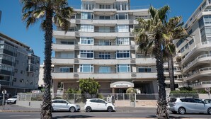 Een hotel met meerdere verdiepingen, balkons, palmbomen en een helderblauwe lucht.