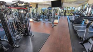 A gym with cardio machines, weight stations, and a mirror wall.