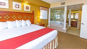 A hotel room with a large bed, a bathroom with a bathtub, and a view of the outside.