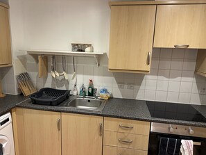 A kitchen with wooden cabinets, a granite countertop, a stainless steel sink, and a dishwasher. - Staying With Ganmos Place (Bracknell)