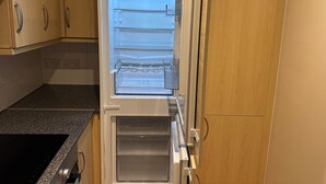 Eine Küche mit integriertem Kühlschrank, einer Arbeitsplatte aus Granit und Holzschränken.