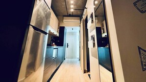 A narrow, modern kitchen with stainless steel appliances and a wooden floor. - Travel VIP Lounge Themed. Private Parking (Monterrey)