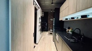 A modern kitchen with wooden cabinets, a black countertop, and a visible sink. - Travel VIP Lounge Themed. Private Parking (Monterrey)
