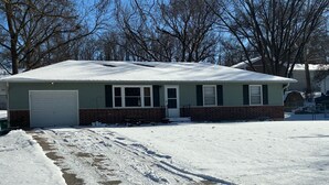 A single-story house with a garage, a brick foundation, and a snow-covered roof. - Kansas City World Cup Rental - PRICED RIGHT (Platte City)