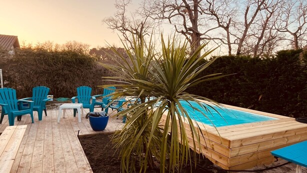 A wooden deck with a pool, surrounded by blue chairs and a potted plant. - Large villa with a marine atmosphere, 20 minutes from beaches and lakes! Ideal for families (Pontenx-les-Forges)