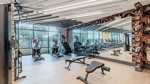 Un gimnasio moderno con máquinas de cardio, pesas libres y bancos.