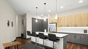 Una cocina moderna con una isla central, taburetes de bar e iluminación colgante.
