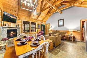 A cozy log cabin interior with a dining area, fireplace, and comfortable seating. - Cabin for 6 w Hot Tub & Game Room (Gatlinburg)