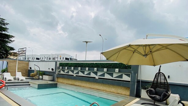A swimming pool with a lifebuoy, lounge chairs, and a hanging chair. - 2020 Hotels katampe. (Abuja)