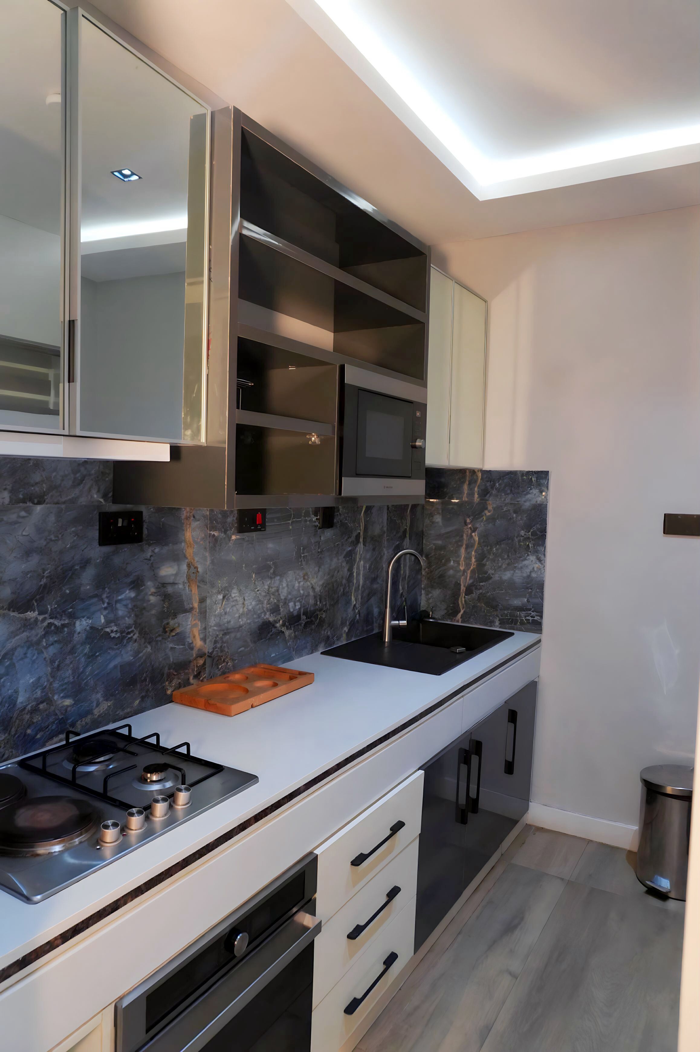 A modern kitchen with a gas stove, a sink, and built-in cabinets.