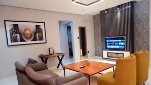 A modern living room with a sofa, a coffee table, and a TV. - 2020 Hotels katampe. (Abuja)
