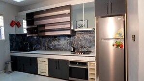 A modern kitchen with a built-in oven, a stainless steel refrigerator, and a marble backsplash. - 2020 Hotels katampe. (Abuja)