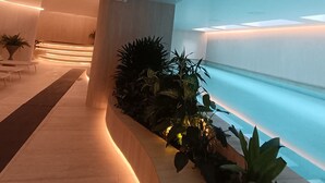Un espace intérieur moderne doté d’un chemin sinueux, de coins salon et d’un élément décoratif aquatique.