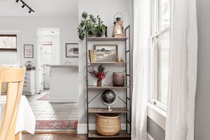 A modern kitchen with white cabinets, a wooden dining table, and a red rug. - The Checkered Flag • Classic Indy Home • Walkable (Indianapolis)