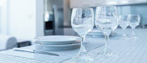 Un comedor limpio y moderno con vajilla y vasos blancos.