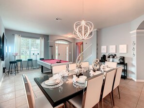 A modern dining area with a pool table, a chandelier, and a coffee station. - EPIC! Themed-Arcade-Theatre-Pool Table-Pool&Spa-3mi>Disney (Kissimmee)