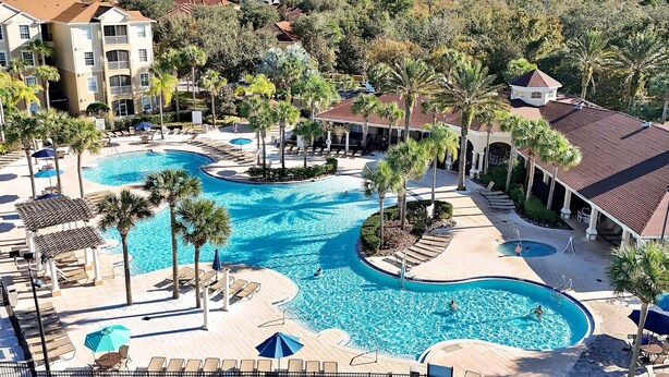 Ein Resort mit großem Schwimmbad, Palmen und Blick auf die Umgebung.