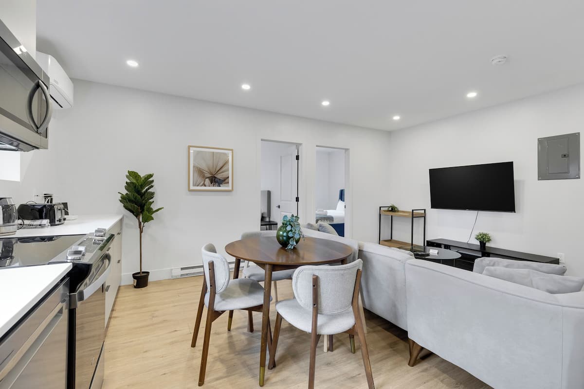 A modern kitchen with a dining area, a flat-screen TV, and a sofa.