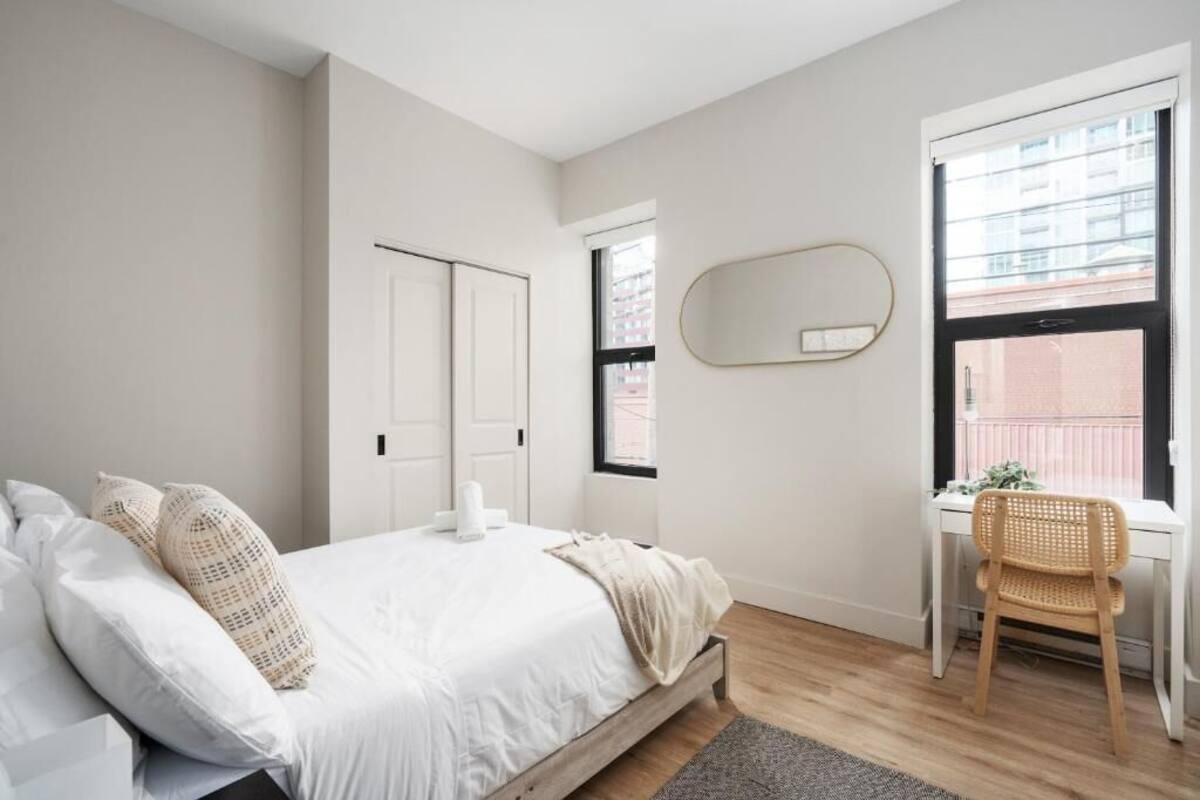 A bedroom with a bed, a desk, a chair, a window, and a door.