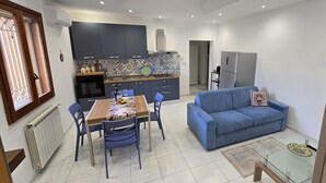 Een moderne keuken met donkere kastjes, een betegelde spatwand en een eethoek met tafel en stoelen.