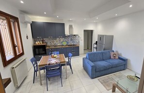 Eine moderne Küche mit dunklen Schränken, einer gefliesten Spritzschutzwand und einem Essbereich mit Tisch und Stühlen.