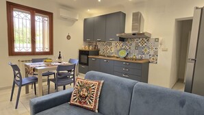 Een moderne keuken met grijze kastjes, een betegelde achterwand en een eethoek met een tafel en stoelen.