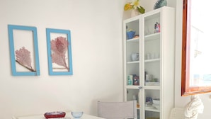 A white room with a table and chairs, a cabinet with glass doors, and a window with a view. - THE WINDOW TO THE SEA (Alghero)