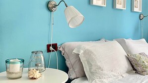 A bedroom with a bed, a bedside table, a lamp, and framed pictures on the wall. - THE WINDOW TO THE SEA (Alghero)